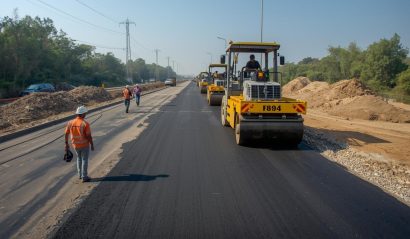 Highway road construction site in India, rollers compacting asphalt, excavators leveling soil, engineers overseeing project, ultra-realistic wide shot.